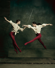 Image showing Two young female ballet dancers like duelists with swords. Ballet and contemporary choreography concept. Creative art photo.