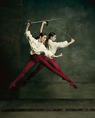 Image showing Two young female ballet dancers like duelists with swords. Ballet and contemporary choreography concept. Creative art photo.