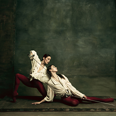 Image showing Two young female ballet dancers like duelists with swords. Ballet and contemporary choreography concept. Creative art photo.