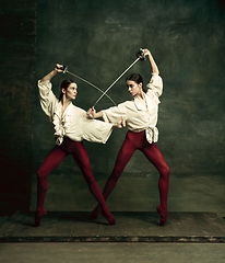 Image showing Two young female ballet dancers like duelists with swords. Ballet and contemporary choreography concept. Creative art photo.