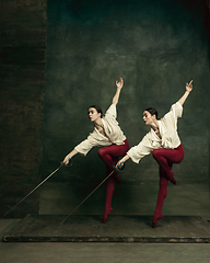 Image showing Two young female ballet dancers like duelists with swords. Ballet and contemporary choreography concept. Creative art photo.