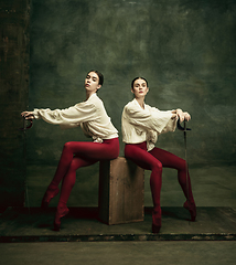 Image showing Two young female ballet dancers like duelists with swords. Ballet and contemporary choreography concept. Creative art photo.