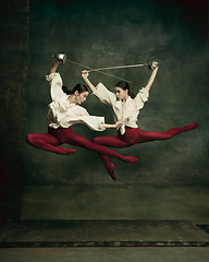 Image showing Two young female ballet dancers like duelists with swords. Ballet and contemporary choreography concept. Creative art photo.