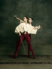 Image showing Two young female ballet dancers like duelists with swords. Ballet and contemporary choreography concept. Creative art photo.