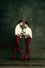 Image showing Two young female ballet dancers like duelists with swords. Ballet and contemporary choreography concept. Creative art photo.