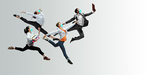 Image showing Happy office workers in face masks jumping and dancing in casual clothes or suit isolated on studio background. Creative collage.