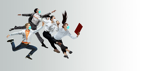 Image showing Happy office workers in face masks jumping and dancing in casual clothes or suit isolated on studio background. Creative collage.