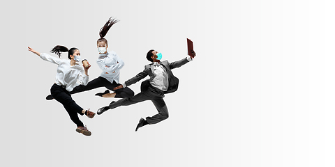 Image showing Happy office workers in face masks jumping and dancing in casual clothes or suit isolated on studio background. Creative collage.