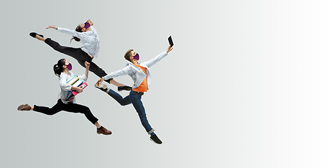 Image showing Happy office workers in face masks jumping and dancing in casual clothes or suit isolated on studio background. Creative collage.