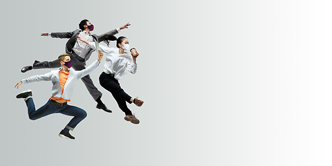 Image showing Happy office workers in face masks jumping and dancing in casual clothes or suit isolated on studio background. Creative collage.