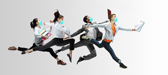 Image showing Happy office workers in face masks jumping and dancing in casual clothes or suit isolated on studio background. Creative collage.