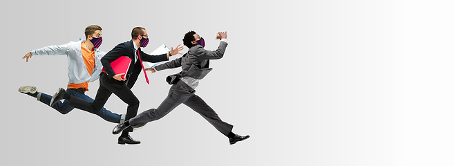 Image showing Happy office workers in face masks jumping and dancing in casual clothes or suit isolated on studio background. Creative collage.