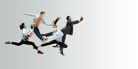 Image showing Happy office workers in face masks jumping and dancing in casual clothes or suit isolated on studio background. Creative collage.