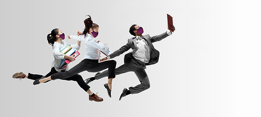 Image showing Happy office workers in face masks jumping and dancing in casual clothes or suit isolated on studio background. Creative collage.