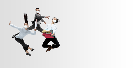 Image showing Happy office workers in face masks jumping and dancing in casual clothes or suit isolated on studio background. Creative collage.