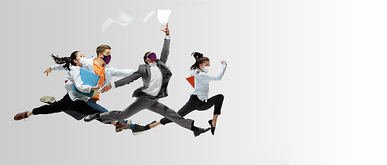 Image showing Happy office workers in face masks jumping and dancing in casual clothes or suit isolated on studio background. Creative collage.