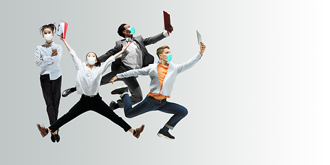 Image showing Happy office workers in face masks jumping and dancing in casual clothes or suit isolated on studio background. Creative collage.