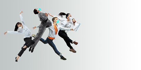 Image showing Happy office workers in face masks jumping and dancing in casual clothes or suit isolated on studio background. Creative collage.