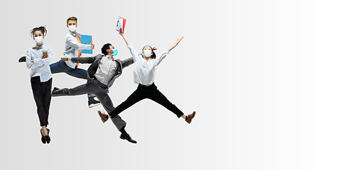 Image showing Happy office workers in face masks jumping and dancing in casual clothes or suit isolated on studio background. Creative collage.