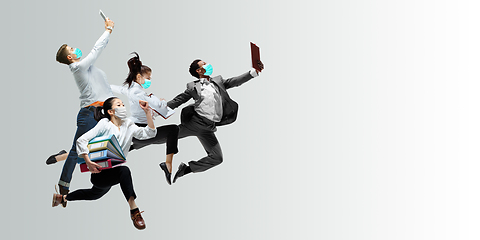 Image showing Happy office workers in face masks jumping and dancing in casual clothes or suit isolated on studio background. Creative collage.