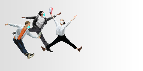 Image showing Happy office workers in face masks jumping and dancing in casual clothes or suit isolated on studio background. Creative collage.