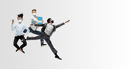 Image showing Happy office workers in face masks jumping and dancing in casual clothes or suit isolated on studio background. Creative collage.