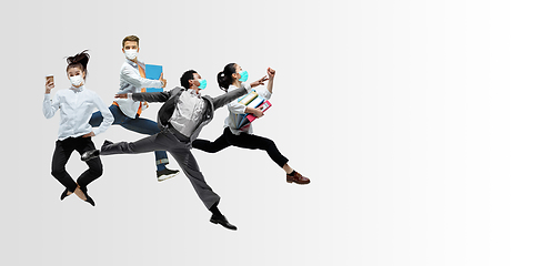 Image showing Happy office workers in face masks jumping and dancing in casual clothes or suit isolated on studio background. Creative collage.