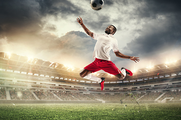 Image showing Young man football player kicking ball during match at stadium. Flyer for ad, design.