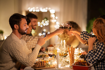 Image showing man with smartphone at dinner party with friends