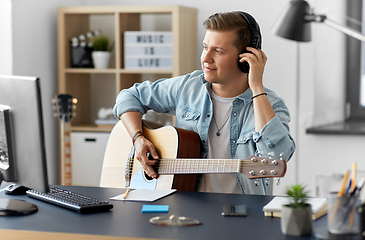 Image showing man in headphones playing guitar at home