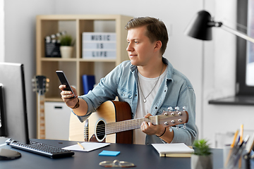 Image showing young man with guitar and smartphone at home