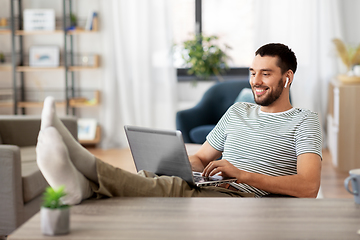 Image showing happy man with laptop and earphones at home