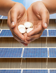 Image showing hands holding money over solar panels