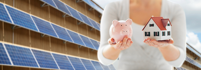 Image showing woman with house and piggy bank over solar panels