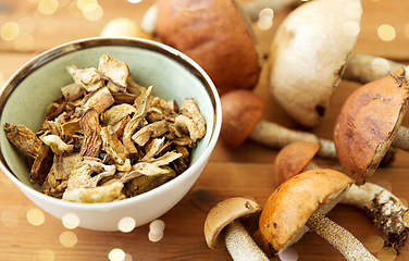 Image showing dried mushrooms in bowl on wooden background