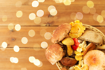 Image showing basket of different edible mushrooms on wood