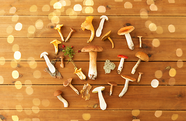 Image showing different edible mushrooms on wooden background