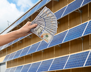 Image showing hands holding money over solar panels