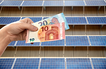 Image showing hands holding money over solar panels