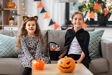 Image showing girls in halloween costumes with candies at home