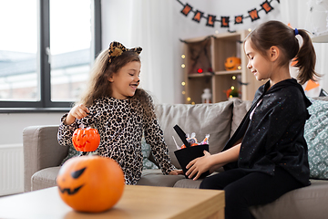 Image showing girls in halloween costumes with candies at home