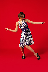 Image showing Old-school fashioned young woman dancing isolated on red background