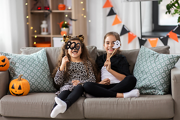 Image showing girls in halloween costumes with pumpkins at home