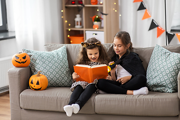 Image showing girls in halloween costumes reading book at home