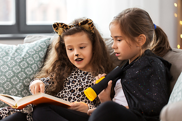 Image showing girls in halloween costumes reading book at home