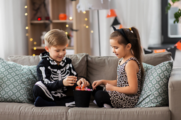 Image showing kids in halloween costumes with candies at home