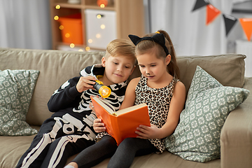 Image showing kids in halloween costumes reading book at home