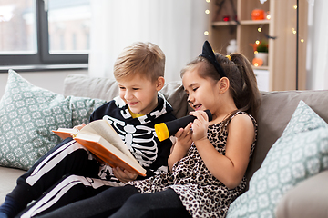 Image showing kids in halloween costumes reading book at home