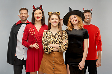 Image showing happy friends in halloween costumes over grey