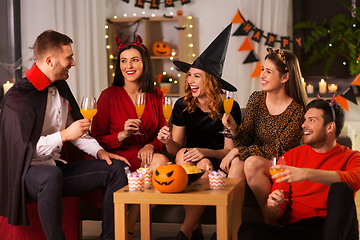 Image showing happy friends in halloween costumes at home party